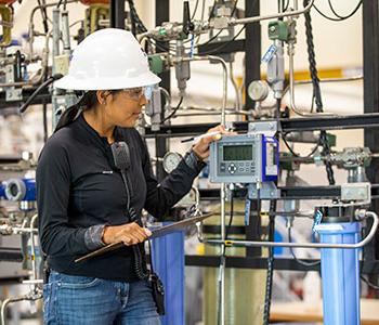 Person wearing white hardhat working on instrumentation controls.